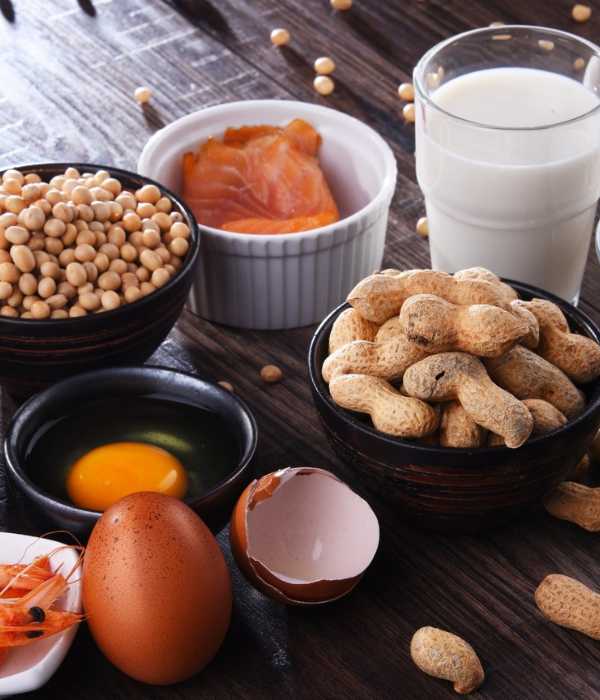 A glass of milk, smoked salmon, peanuts and eggs displayed on a table.