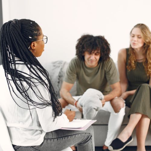 A couple sit on a couch and listen to their dietitian.