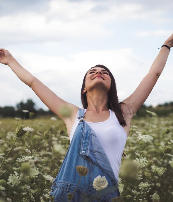 A woman stands in a field of flowers.