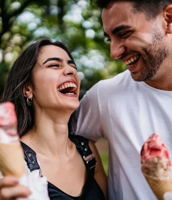 A couple laugh together while holding their ice cream.