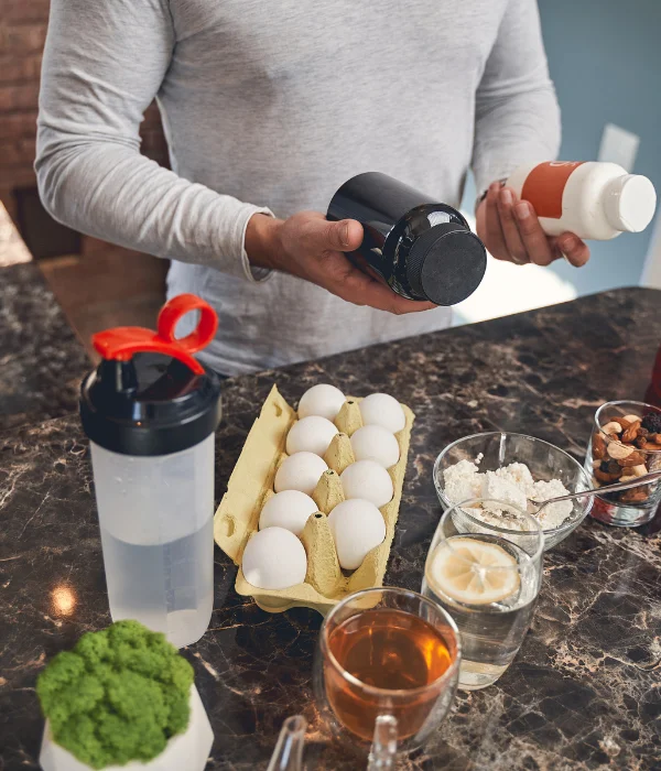 A man holds two supplement bottles.