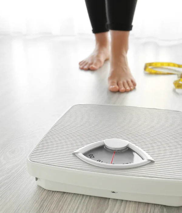 A woman stands behind a scale.